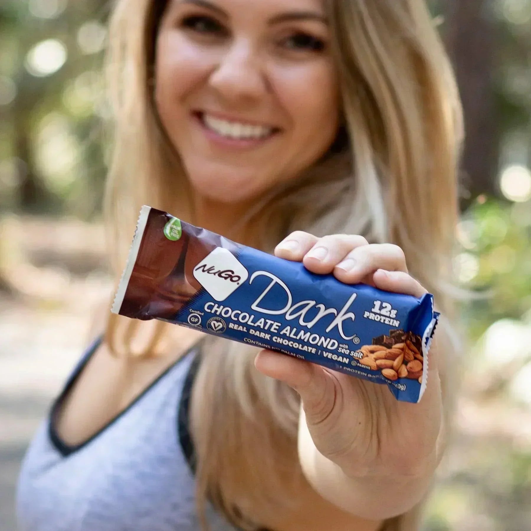 Woman Smilling and holding a Chocolate Almond Bar close up