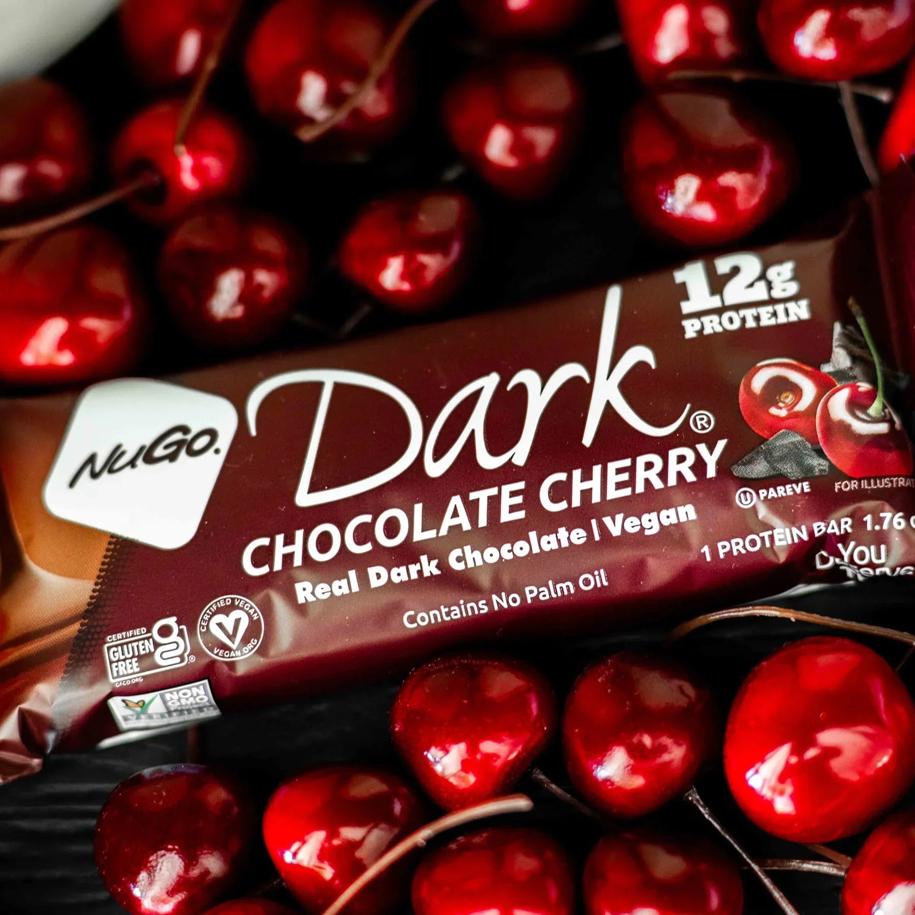 NuGo Dark Chocolate Cherry on a background of fresh cherries