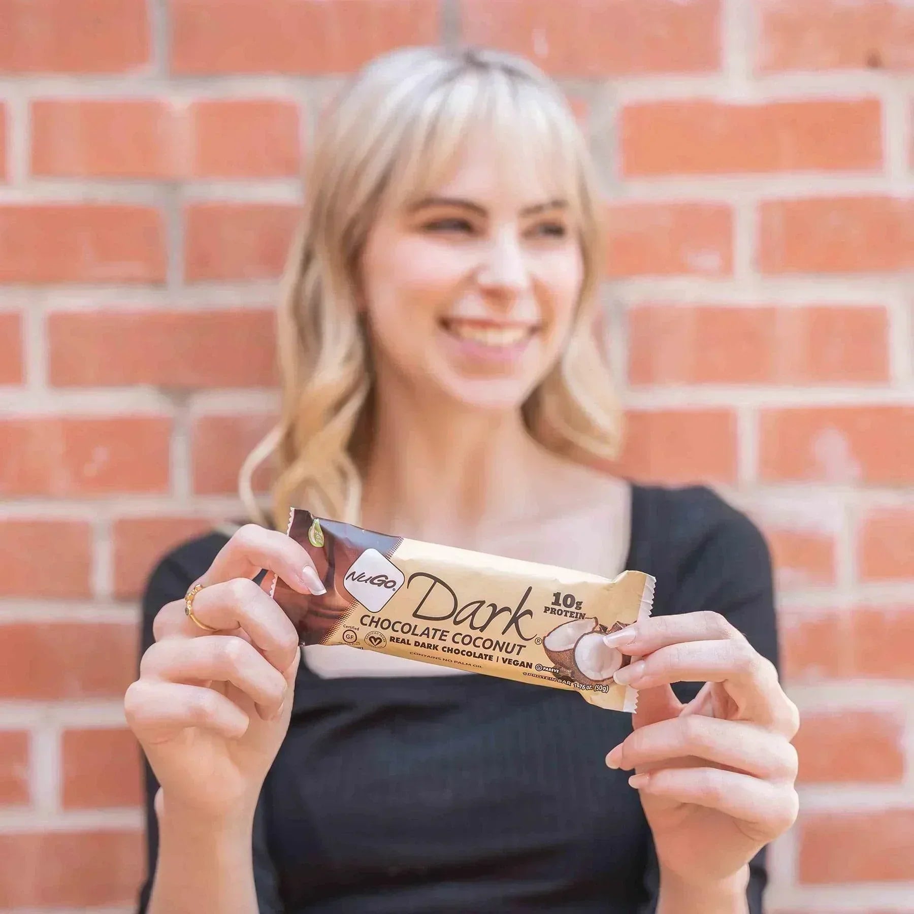Woman hold Chocolate Coconut Bar against Brick Wall