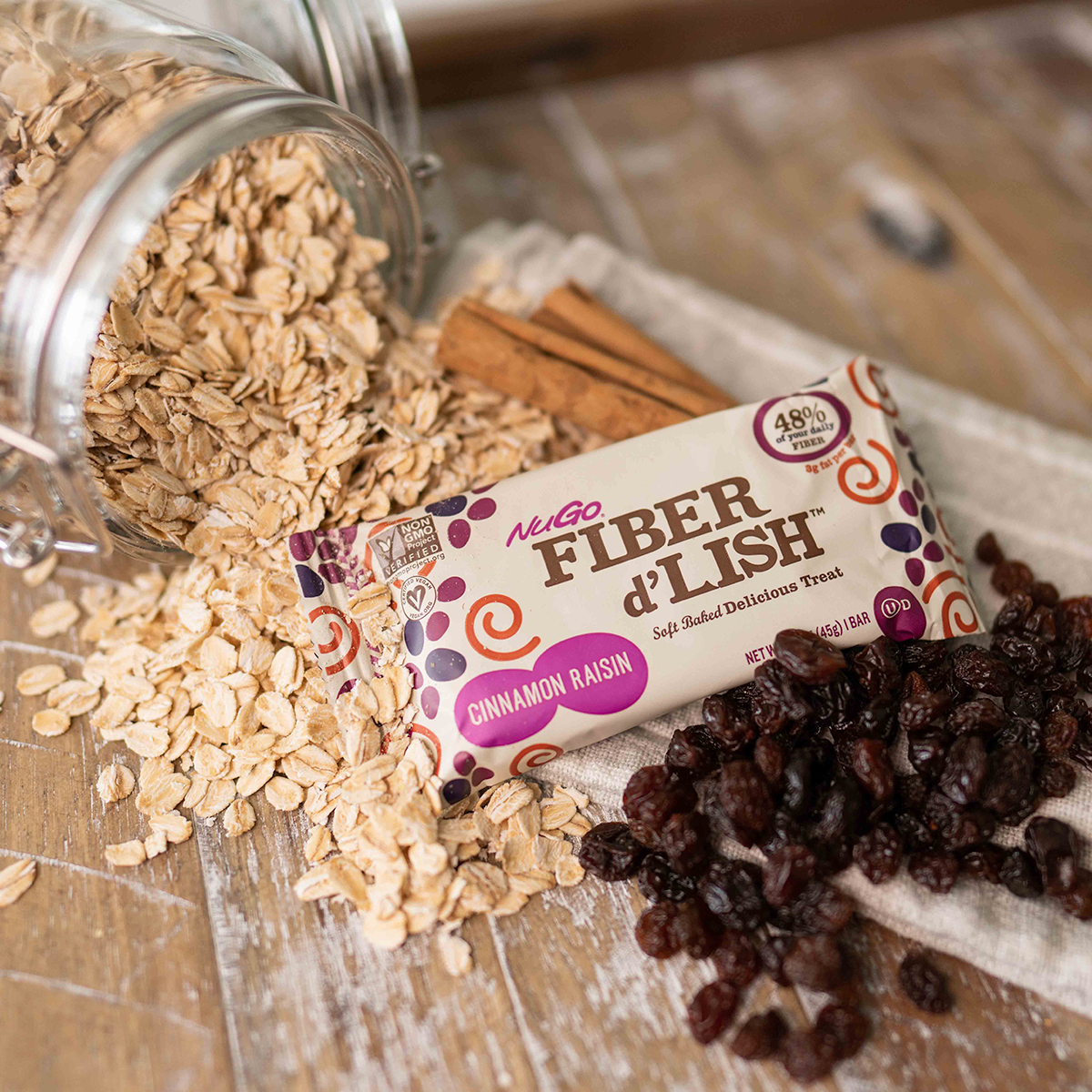 Spilled Oats from glass jar next to NuGo Fiber Cinnamon Raisin