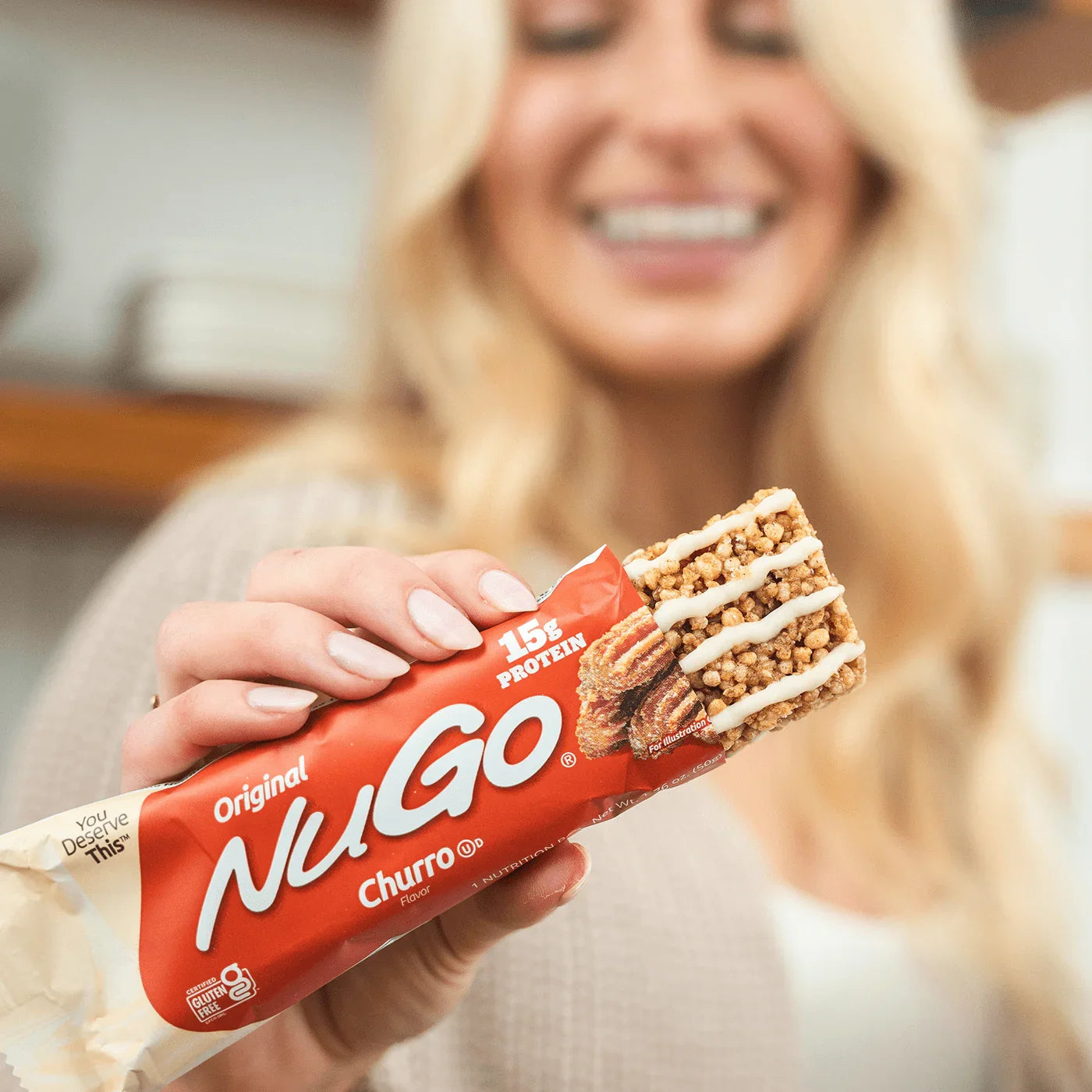 Person holding a NuGo Churro protein bar with a blurred background