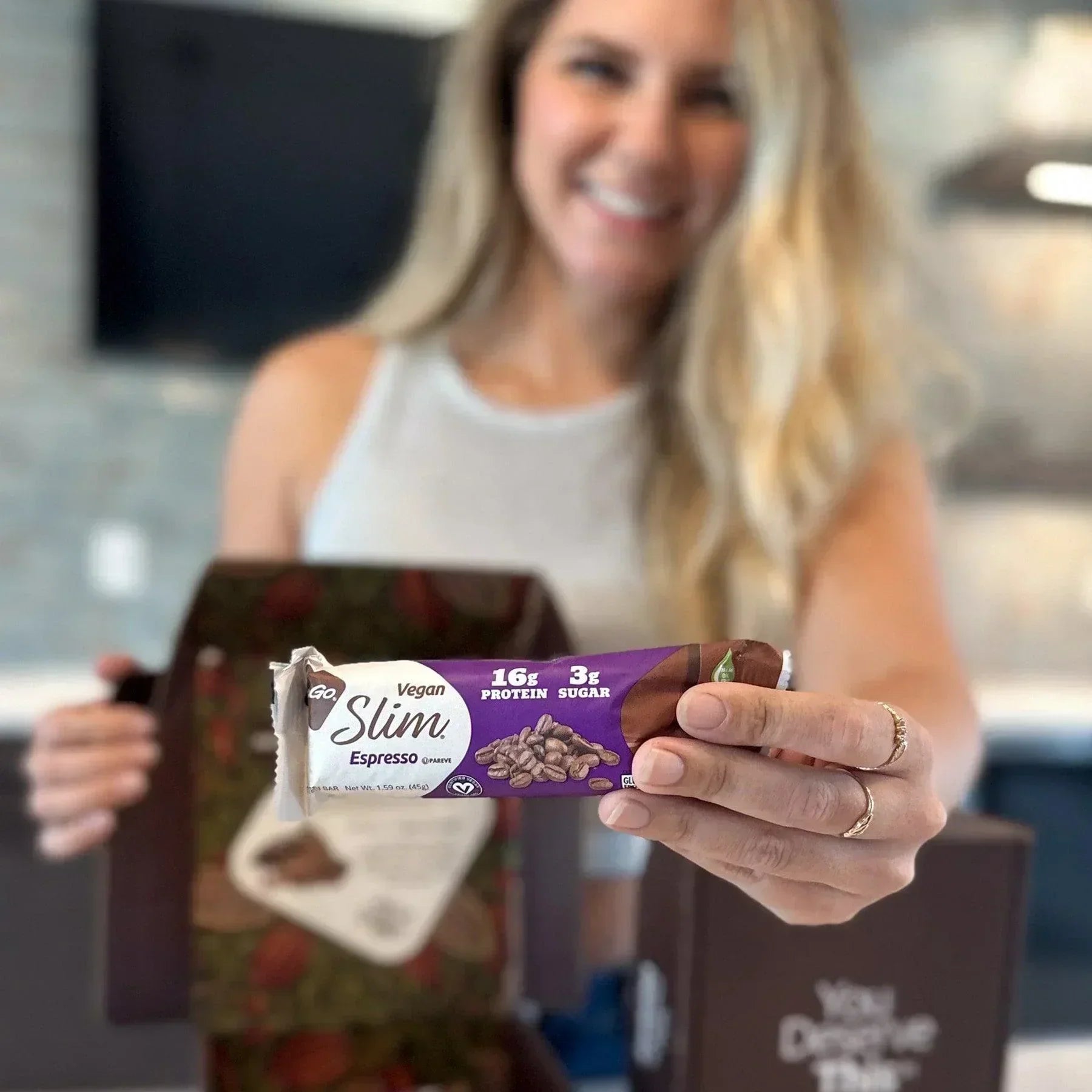 Woman holding out NuGo Slim Espresso from box