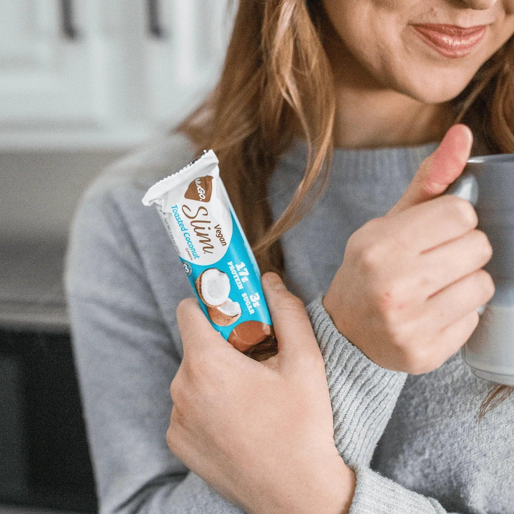 Woman holding a NuGo Slim Toasted Coconut in her fist
