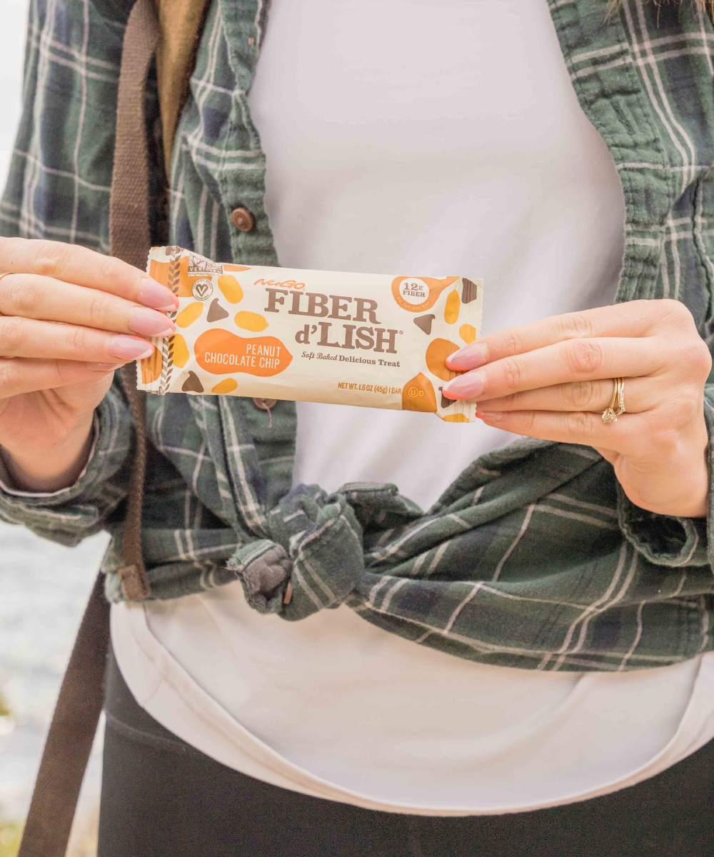 Close up NuGo Fiber Peanut Chocolate Chip in front of womans body