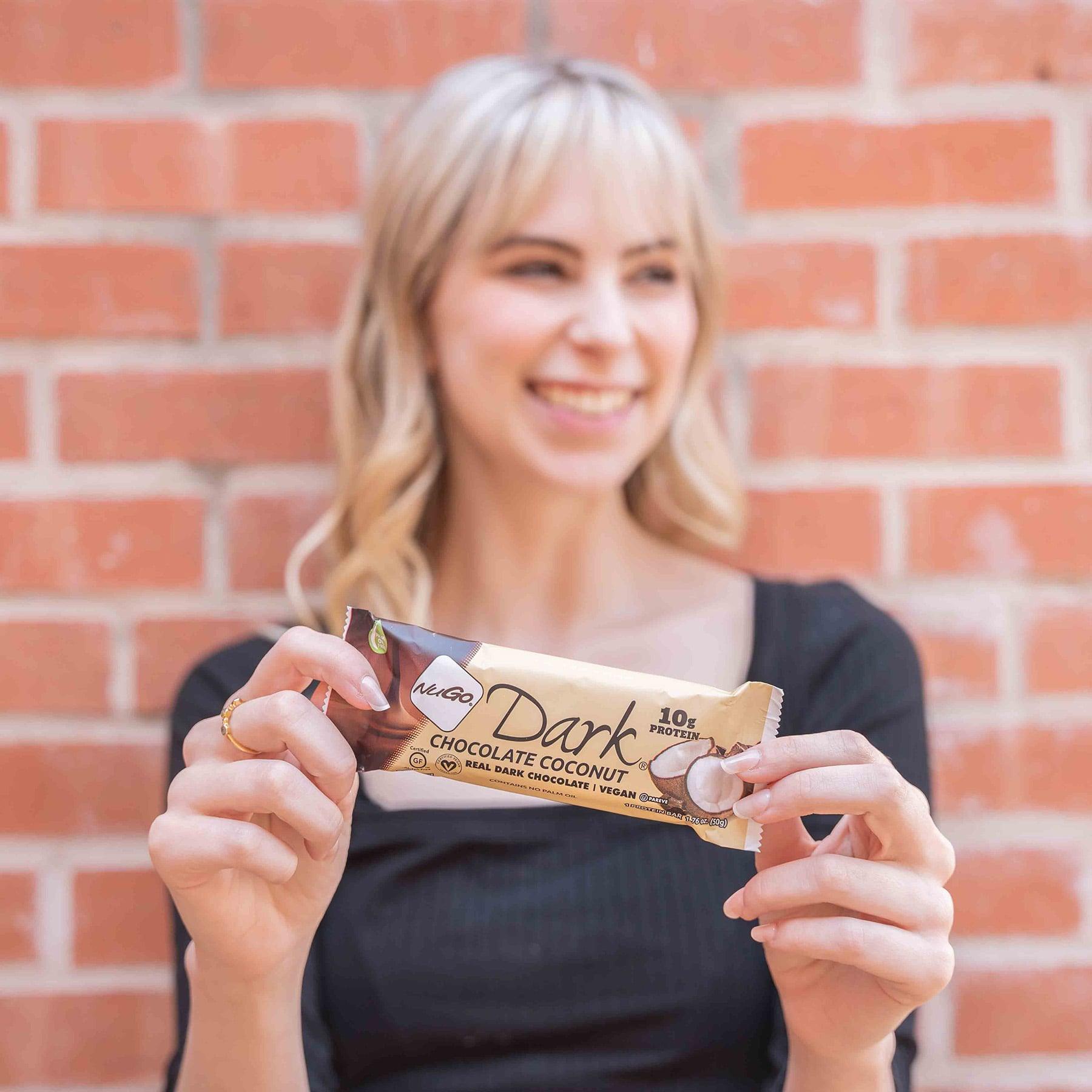 Woman hold Chocoalte Coconut Bar against Brick Wall