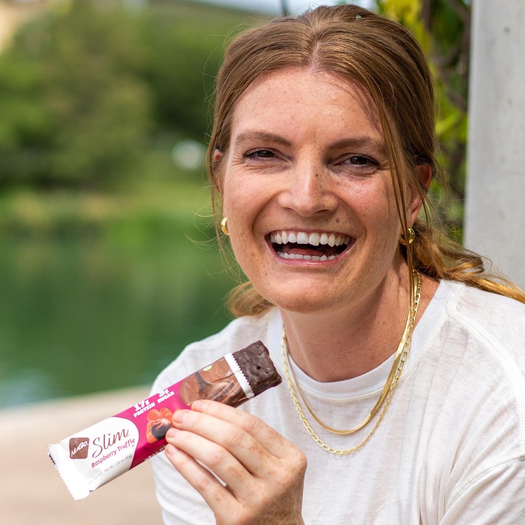 Smiling Woman eating NuGo Slim Raspberry Truffle Bar