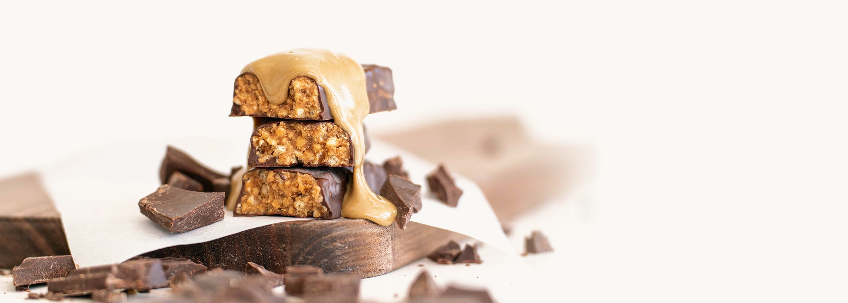 NuGo Slim Creunchy Peanut Butter bar drizzled in peanut butter and surrounded by Chocolate pieces